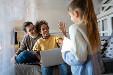 Evde dijital tabletle oynayan genç bekar baba ve gülümseyen kızlar. Dijital tablet kullanan neşeli ve heyecanlı kızları olan genç ebeveynler.