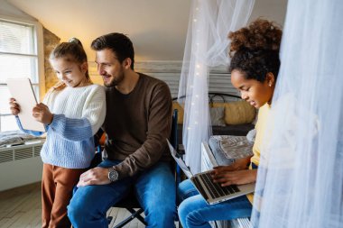 Tekerlekli sandalyede engelli bir baba, eğlenmek, çalışmak ya da sosyal medyada çalışmak için ırklar arası kızlarıyla dijital cihazlar kullanıyor.