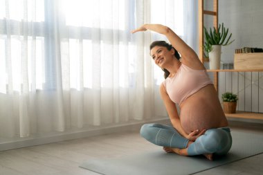 Evde çalışan hamile bir kadının portresi. Hamile kadın evde yoga yapıyor. Hamilelik yogası ve fitness.