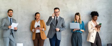 Ofisteki dijital cihazları kullanarak gülümseyen bir yönetici ekibi. Çeşitli profesyonel liderler yöneticiler ve çalışanlar takım çalışmasında çalışan dijital finans projesini tartışıyor.