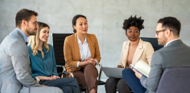 Tam konsantrasyon. Takım olarak çalışan ve kurumsal ofiste iletişim kuran bir grup genç iş adamı.