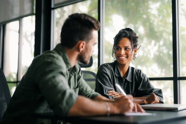 Çeşitli, yetenekli bir takım, bir iş toplantısı sırasında parlak bir ofis alanında etkili bir şekilde işbirliği yapar. Birlikte çalışan başarılı iş arkadaşlarından oluşan yaratıcı bir grup