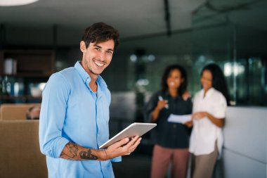 Ofiste dijital tablet kullanarak çalışan bir grup mutlu ve çeşitli profesyonel iş adamları. Çok ırklı bir genç girişim ekibi bir proje üzerinde çalışıyor.