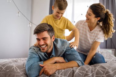 Çok ırklı mutlu bir aile evde eğleniyor, ebeveynler ve küçük çocuklar birlikte kaliteli zaman geçiriyor. Anne, baba ve oğulları birlikte oynayıp gülümsüyor.