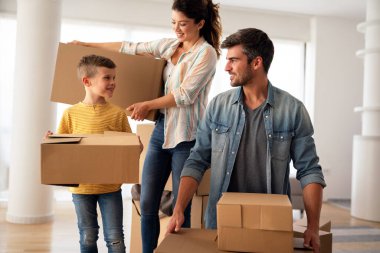 Taşındığı gün yeni evde karton kutuları olan mutlu bir aile. İpotek, aile ve gayrimenkul konsepti, mutlu anne, baba ve çocuk kutuları yeni eve taşınıyor.