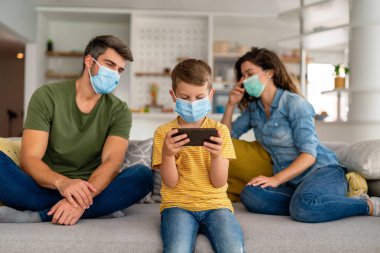 Virüsü, gribi ve kirliliği önlemek için koruyucu maske takan üzgün bir aile. Kirlenmiş hava konseptinden aile koruması