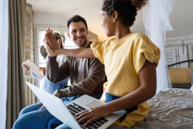 Tekerlekli sandalyede engelli bir baba, eğlenmek, çalışmak ya da sosyal medyada çalışmak için ırklar arası kızlarıyla dijital cihazlar kullanıyor.
