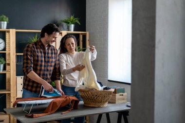 Evde ev işleri yapan ve birlikte ütü yapan genç bir çift. İnsanların mutluluk kavramı.