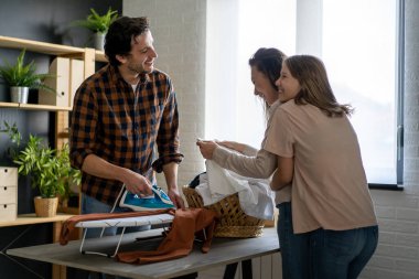 Mutlu çoklu etnik aile ev işlerini birlikte yapıyor, ütü yapıyor, evde birlikte ev işi yapıyor..