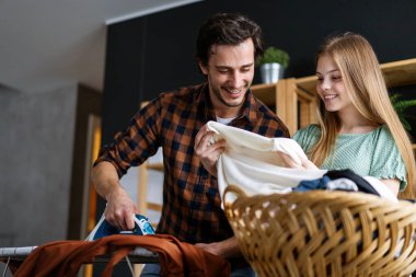 Mutlu bir baba ve kızı evde ev işleri yapıyor ve birlikte ütü yapıyor. İnsanların mutluluk kavramı.