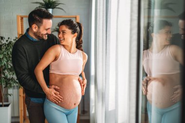 Aşk, şefkat, ilişki ve yeni aile kavramı. Aşık bir adam hamile karısına sarılır, birlikte bebeklerin gelmesini beklerler.