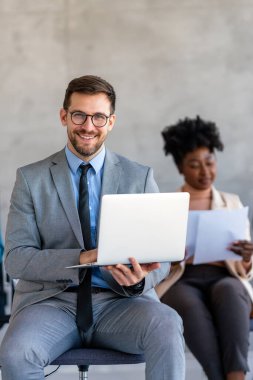 Genç, mutlu ve başarılı genç iş adamı şirket ofisinde çalışıyor ve gülümsüyor. İş başarısı erkek kavramı