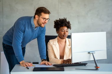 Ofiste yeni bir proje üzerinde çalışırken gülen iş adamları. Modern bir çalışma alanında çalışırken bilgisayar kullanan bir grup farklı iş adamı..