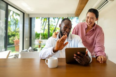 Genç ve çok ırklı çift evde bilgisayar ve dijital cihaz kullanırken eğleniyor. İnsanlar, teknoloji, online yaşam tarzı konsepti