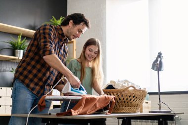 Mutlu bir baba ve kızı evde ev işleri yapıyor ve birlikte ütü yapıyor. İnsanların mutluluk kavramı.