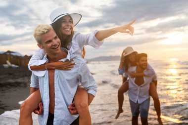 Bir grup neşeli, kaygısız genç insan, çoklu etnik arkadaşlar sırt sırta verip dışarıda kumsalda boş zaman geçirmekten keyif alıyorlar.