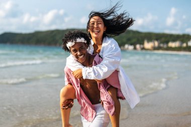 Mutlu çift kumsalda eğleniyor, romantik bir ortamda birlikte gülüyor, aşklarını güçlendiriyor ve güneşin tadını çıkarıyor.