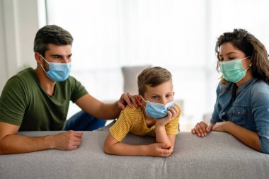 Virüsü, gribi ve kirliliği önlemek için koruyucu maske takan üzgün bir aile. Kirlenmiş hava konseptinden aile koruması