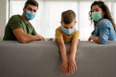 Virüsü, gribi ve kirliliği önlemek için koruyucu maske takan üzgün bir aile. Kirlenmiş hava konseptinden aile koruması