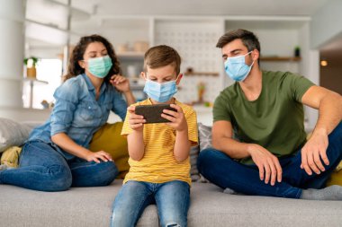 Virüsü, gribi ve kirliliği önlemek için koruyucu maske takan üzgün bir aile. Kirlenmiş hava konseptinden aile koruması