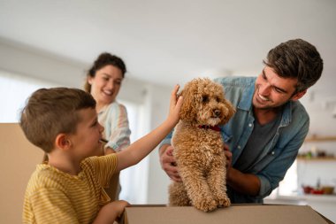 Taşındığı gün yeni evde karton kutuları olan mutlu bir aile. İpotek, aile ve gayrimenkul konsepti, mutlu anne, baba ve çocuk kutuları yeni eve taşınıyor.