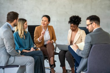 Ofiste yeni bir proje üzerinde çalışırken gülen iş adamları. Modern bir çalışma alanında çalışırken bilgisayar kullanan bir grup farklı iş adamı..