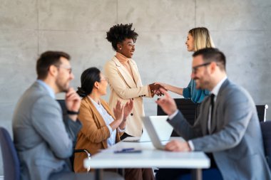 Ofiste yeni bir proje üzerinde çalışırken gülen iş adamları. Modern bir çalışma alanında çalışırken bilgisayar kullanan bir grup farklı iş adamı..