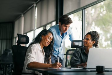 İş projesi ekibi şirket ofisindeki toplantı odasında birlikte çalışıyor.