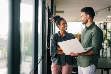 Tablet teknolojisi kullanarak çalışan iki iş adamından oluşan idari ekip şirket ofisinde yürüyor. Mutlu profesyonel gülümseyen işadamı ve iş kadını iş yerinde sohbet ediyorlar.