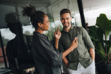 İki farklı etnik çeşitlilikte mutlu iş adamı şirket ofisinde dizüstü bilgisayar kullanarak konuşuyorlar. İş yerindeki meşgul iş adamları ve kadın meslektaşları.