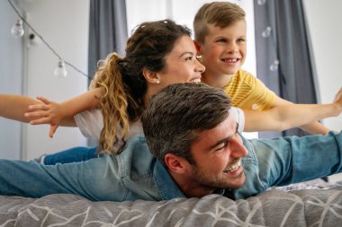 Çok ırklı mutlu bir aile evde eğleniyor, ebeveynler ve küçük çocuklar birlikte kaliteli zaman geçiriyor. Anne, baba ve oğulları birlikte oynayıp gülümsüyor.