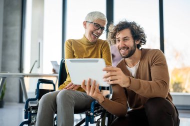 Tekerlekli sandalyedeki kadına yardım etmek, modern ofiste sohbet etmek. Takım çalışması, işyeri, iş dünyası, çeşitlilik, işbirliği, destek