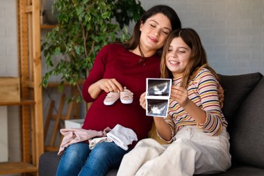 Anne ve kızının yeni doğan bebek kıyafetlerini inceleyip yeni bir aile üyesinin gelişini heyecanla beklemeleri ne kadar da iç açıcı.