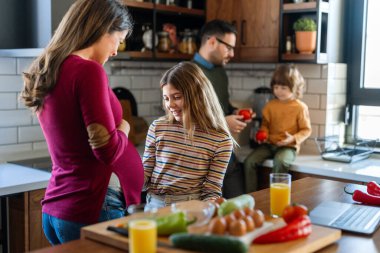 Mutlu aile hafta sonu kahvaltısı sırasında mutfakta eğleniyor. Hamile anne, heyecanlı kızıyla hamileliğinin son üç ayının tadını çıkarıyor..