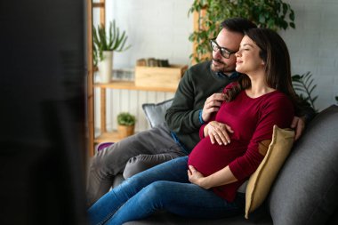 Güzel, genç bir çift, hamile bir eş ve kocası karılarının karnına dokunuyor. Yeni aile, mutlu çift kavramı.