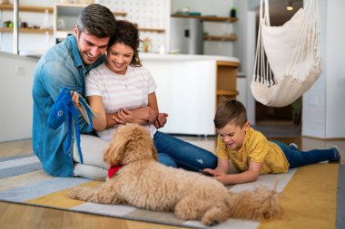 Mutlu bir aile oyunu, evde köpekle eğlenmek. Portre anne, baba ve çocuk oturma odasında kaliteli zaman, sevgi ve bakım için birlikte hafta sonu