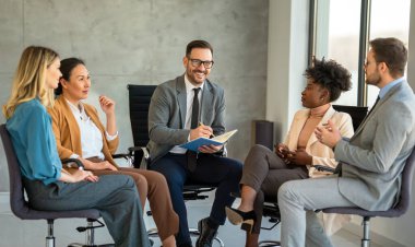 Ofiste yeni bir proje üzerinde çalışırken gülen iş adamları. Modern bir çalışma alanında çalışırken bilgisayar kullanan bir grup farklı iş adamı..