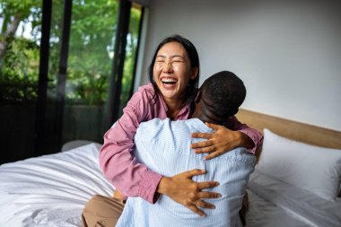 Parlak oturma odalarında neşeli bir şekilde gülümseyen, sıradan kıyafetler giyen ve neşeli hareketlerle mutluluklarını ifade eden genç bir çift.