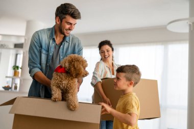 Taşındığı gün yeni evde karton kutuları olan mutlu bir aile. İpotek, aile ve gayrimenkul konsepti, mutlu anne, baba ve çocuk kutuları yeni eve taşınıyor.
