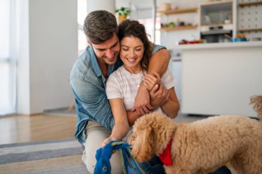 Evcil köpeklerini tırmalayan, evde yerde oturan mutlu çok ırklı çiftin portresi. Mutlu kadın ve erkek evlatlık köpekleriyle oynuyor ve birlikte kaliteli zaman geçiriyorlar.