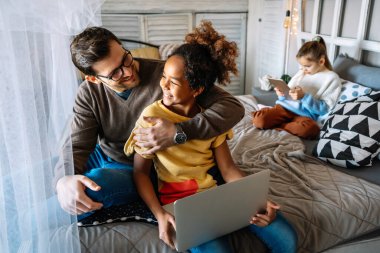 Evde dijital tabletle oynayan genç bekar baba ve gülümseyen kızlar. Dijital tablet kullanan neşeli ve heyecanlı kızları olan genç ebeveynler.