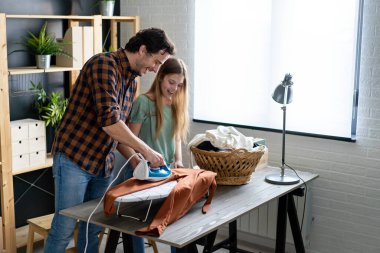 Mutlu bir baba ve kızı evde ev işleri yapıyor ve birlikte ütü yapıyor. İnsanların mutluluk kavramı.