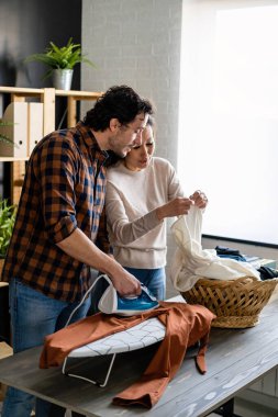 Evde ev işleri yapan ve birlikte ütü yapan genç bir çift. İnsanların mutluluk kavramı.