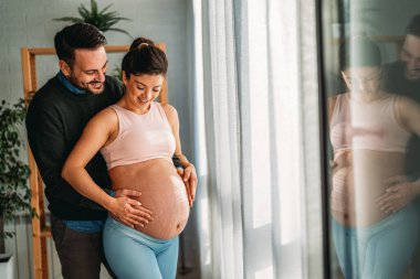 Aşk, şefkat, ilişki ve yeni aile kavramı. Aşık bir adam hamile karısına sarılır, birlikte bebeklerin gelmesini beklerler.