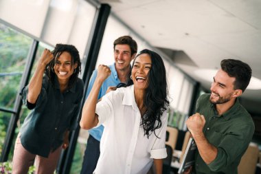 Ofiste dijital tablet kullanarak çalışan bir grup mutlu ve çeşitli profesyonel iş adamları. Çok ırklı bir genç girişim ekibi bir proje üzerinde çalışıyor.