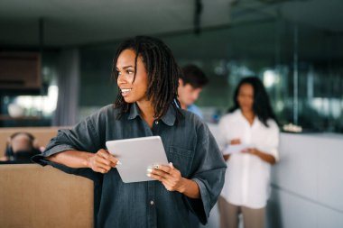 Gülümseyen Afro-Amerikan başarılı iş kadını, serbest çalışan, iş arkadaşı iş yerinde dijital cihaz kullanan kadın lider.