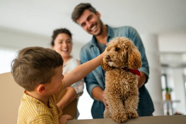 Taşındığı gün yeni evde karton kutuları olan mutlu bir aile. İpotek, aile ve gayrimenkul konsepti, mutlu anne, baba ve çocuk kutuları yeni eve taşınıyor.