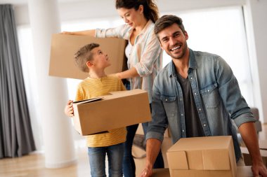 Yeni bir apartmanda kutularla taşınan çocuklu mutlu bir aile. Ev sahibi, taşınma günü için heyecanlı aile, taşınma ve kiralama konsepti