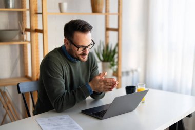 Kendine güvenen iş adamı yönetici koçu. Günlük kıyafetlerini giyip dizüstü bilgisayar kullanıyor, sanal görüşme yapıyor, profesyonel eğitim pazarlığı yapıyor, uzaktan kumandayı evden yapıyor..