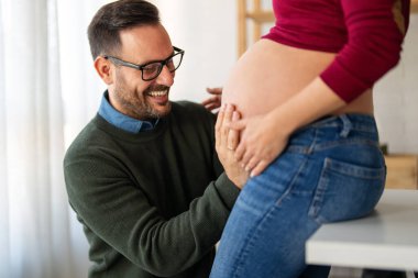 Aşk, şefkat, ilişki ve yeni aile kavramı. Aşık bir adam hamile karısına sarılır, birlikte bebeklerin gelmesini beklerler.
